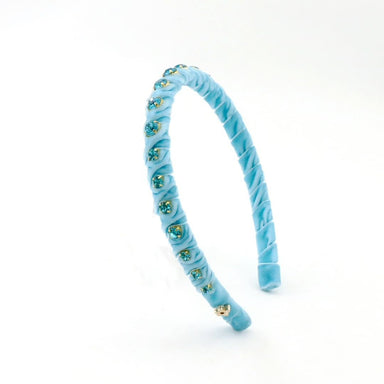 A light blue velvet headband decorated with small gold and green rhinestone clusters, shown on a plain white background.