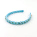 A light blue velvet headband decorated with small gold rhinestone accents and blue crystals, displayed on a clean white background.