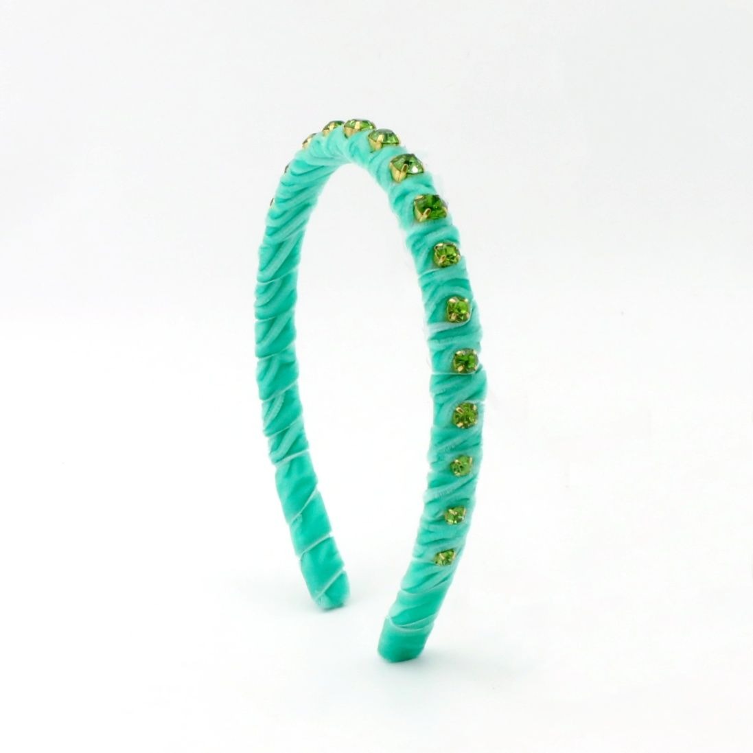 A twisted turquoise velvet headband embellished with small green faceted rhinestones, shown on a plain white background.