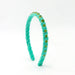 A twisted turquoise velvet headband embellished with small green faceted rhinestones, shown on a plain white background.