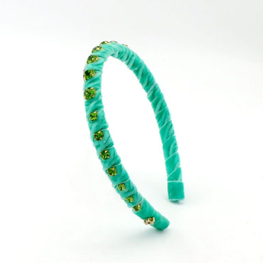 A turquoise velvet headband with twisted detailing and small green rhinestone embellishments, shown on a plain white background.