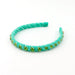 A turquoise braided headband embellished with small green rhinestones, displayed on a clean white background.