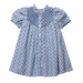 A light blue cotton dress for toddlers or girls, featuring a small red and white carnation print, a smocked blue yoke with white buttons, and short puff sleeves.