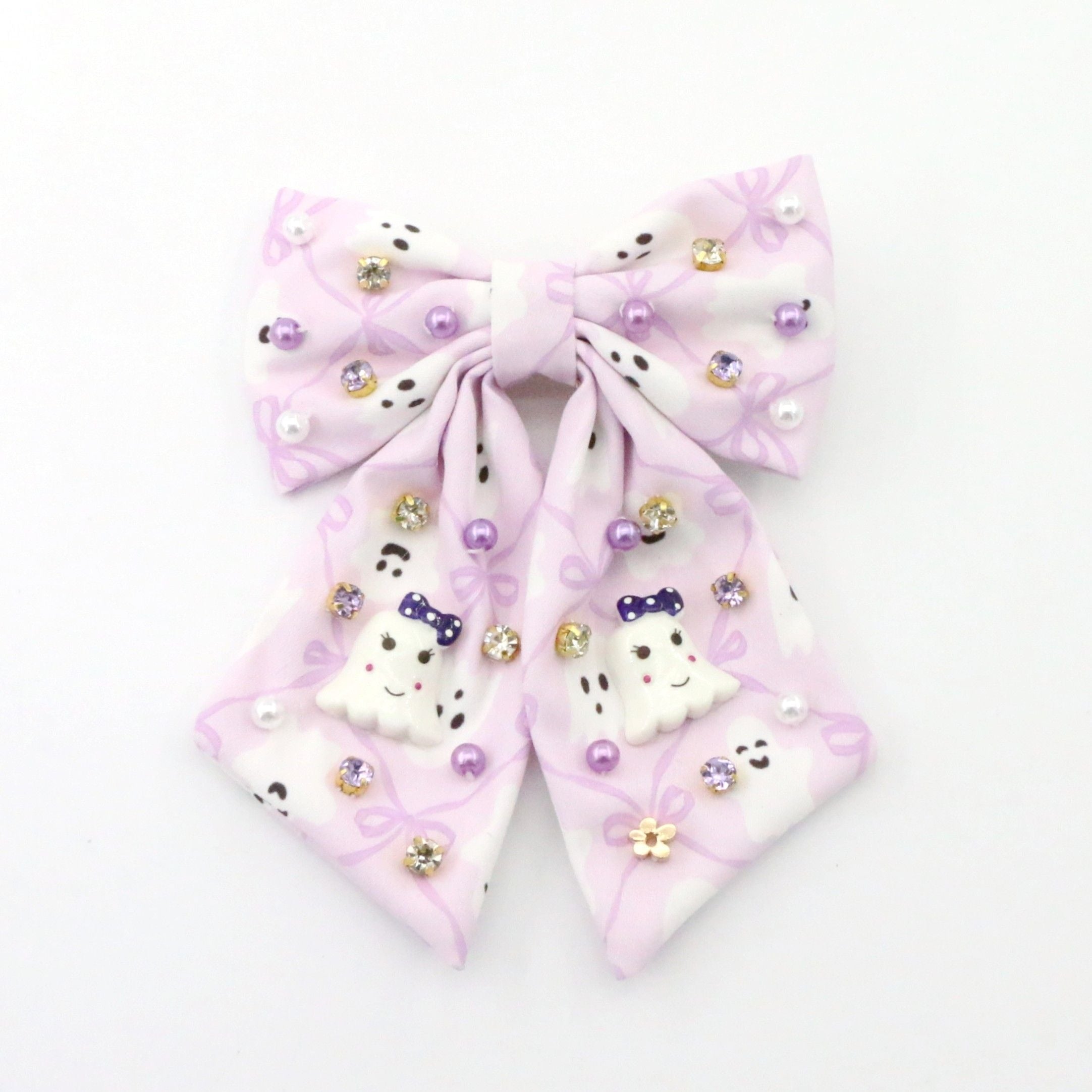 A light purple and white hair bow decorated with small rhinestones, pearl-like beads, and cute Halloween ghosts on a plain white background.