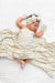 A baby lying in blanet with a delicate floral print, a matching bow headband, and two matching mittens, all in a soft cream color with light blue and tan floral motifs.