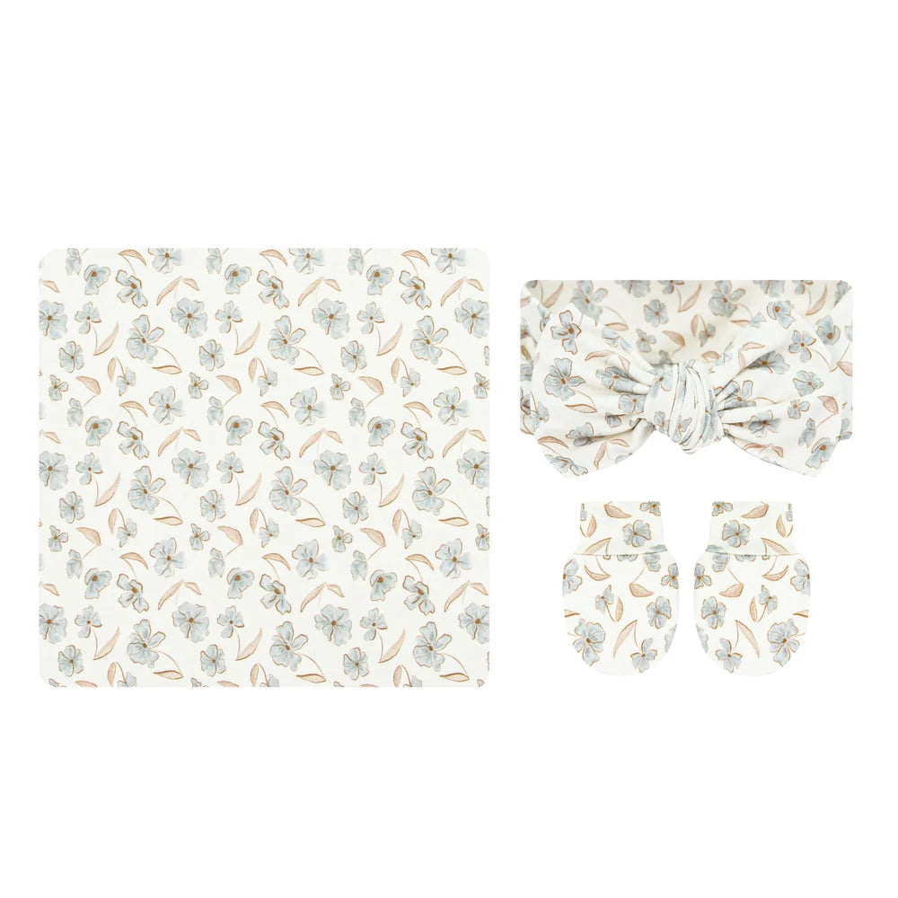 A baby accessory set featuring a square fabric cloth with a delicate floral print, a matching bow headband, and two matching mittens, all in a soft cream color with light blue and tan floral motifs.