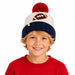 A young boy wearing a knit winter beanie with a red pom-pom, cream knit body, navy blue brim, and a brown football graphic on the front, photographed against a plain white background.