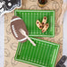 Football-themed place with food and cutlery on a tablecloth with football patterns.