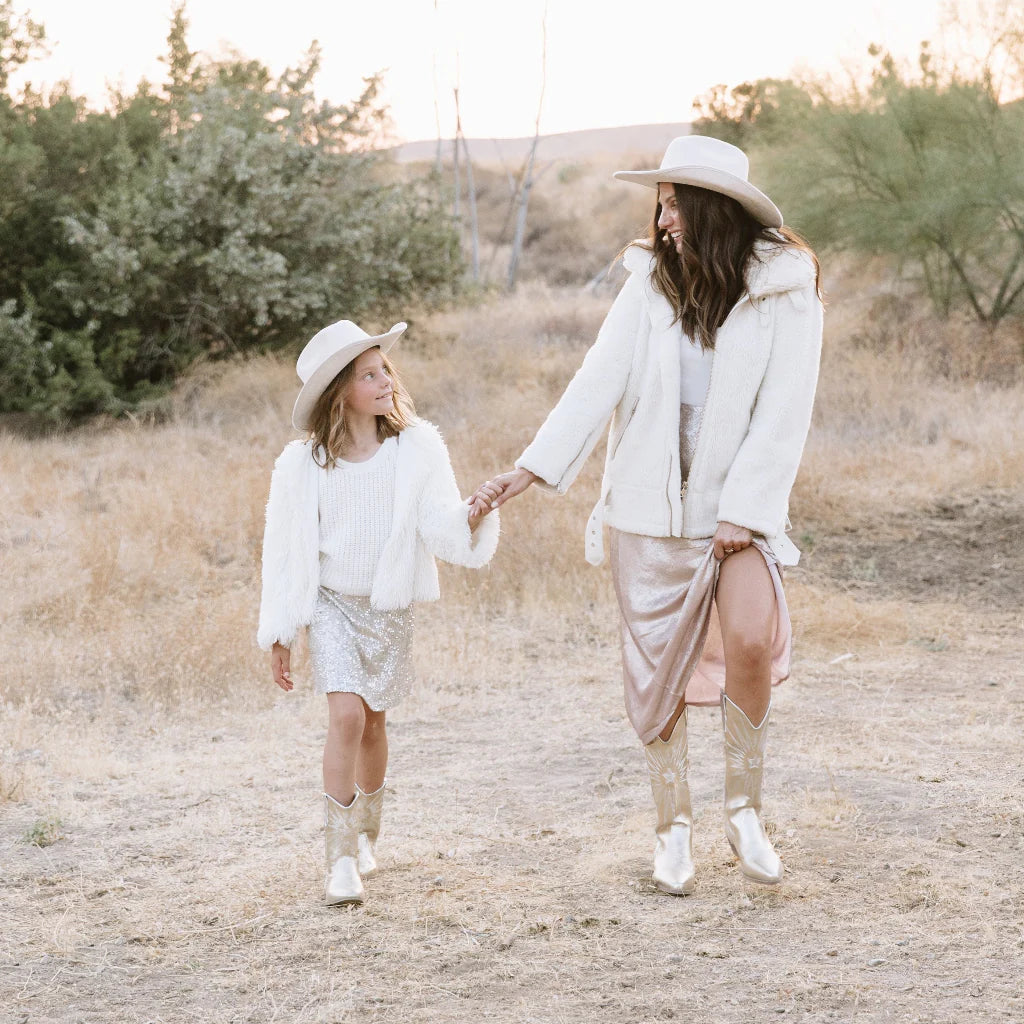 Two people walking hand in hand on a dirt path with trees in the background