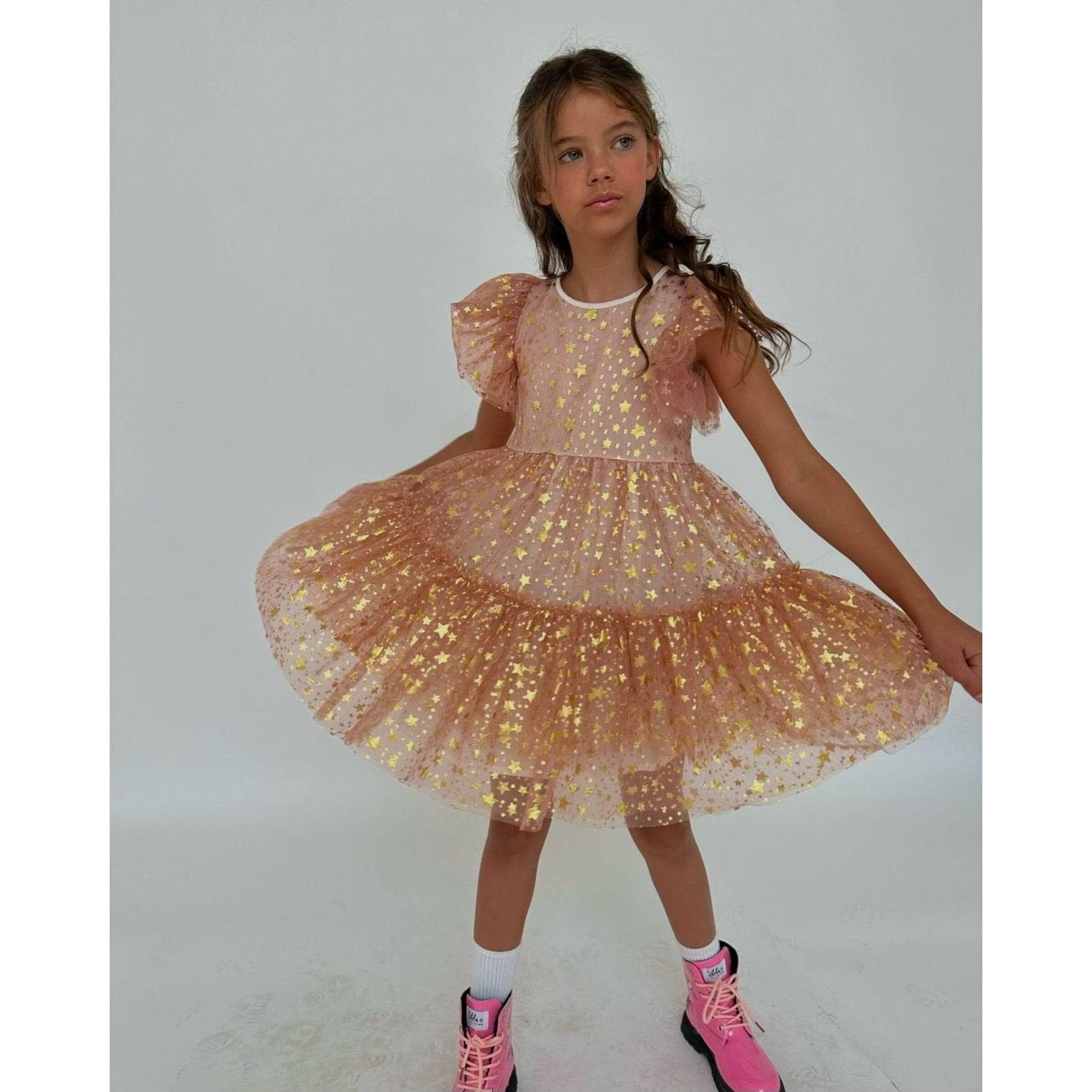 girl wearing blush colored tulle dress covered in gold metallic stars