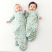 Two babies wearing matching green sleep sacks with a golf print on a white background