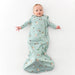 A baby lying on their back wearing a mint green long-sleeve sleep sack with a golf print, set against a plain white background.