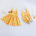 Yellow plaid dress and romper set on a light gray background with decorative items.