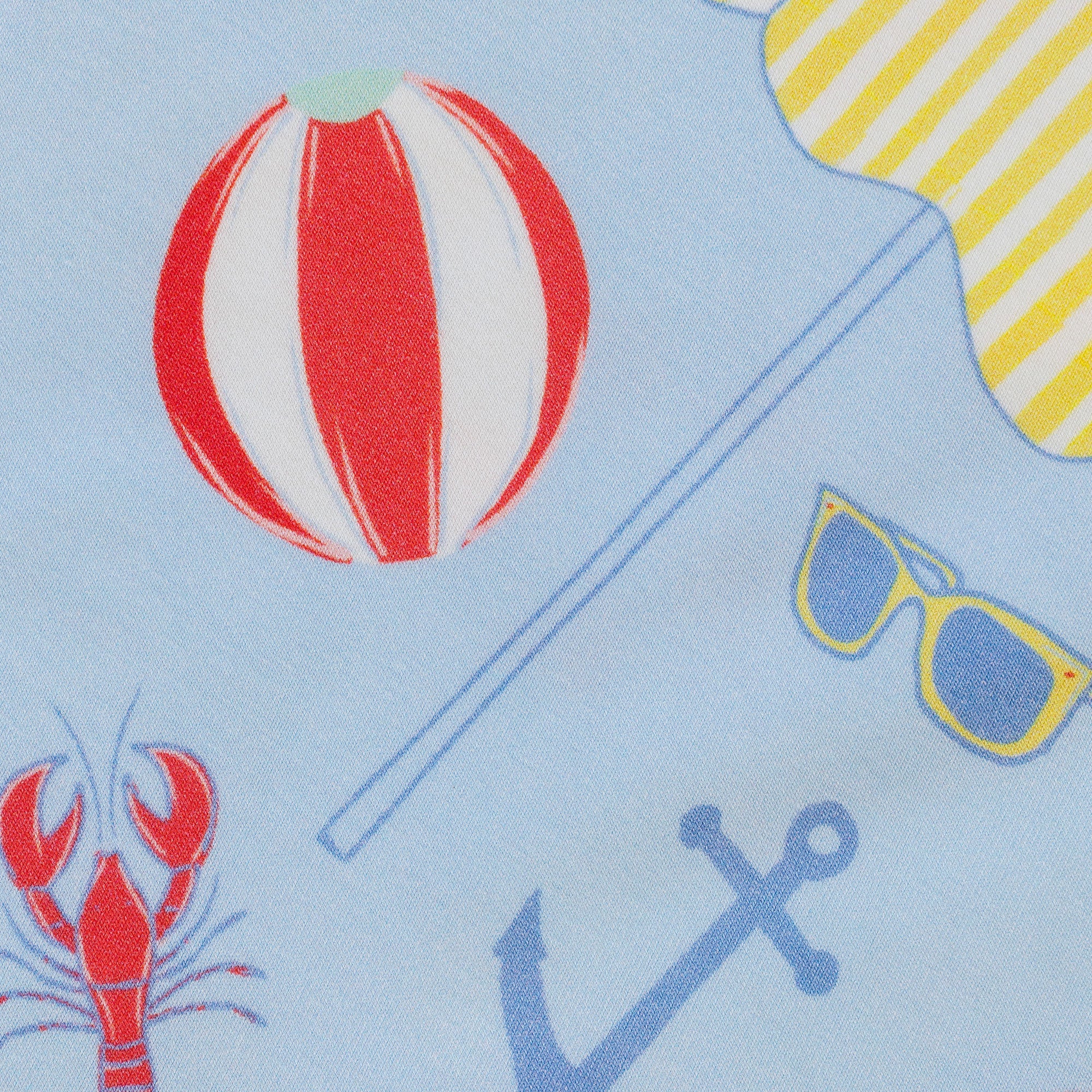 Children's fabric with beach-themed elements including a ball, sunglasses, anchor, and lobster on a light blue background.