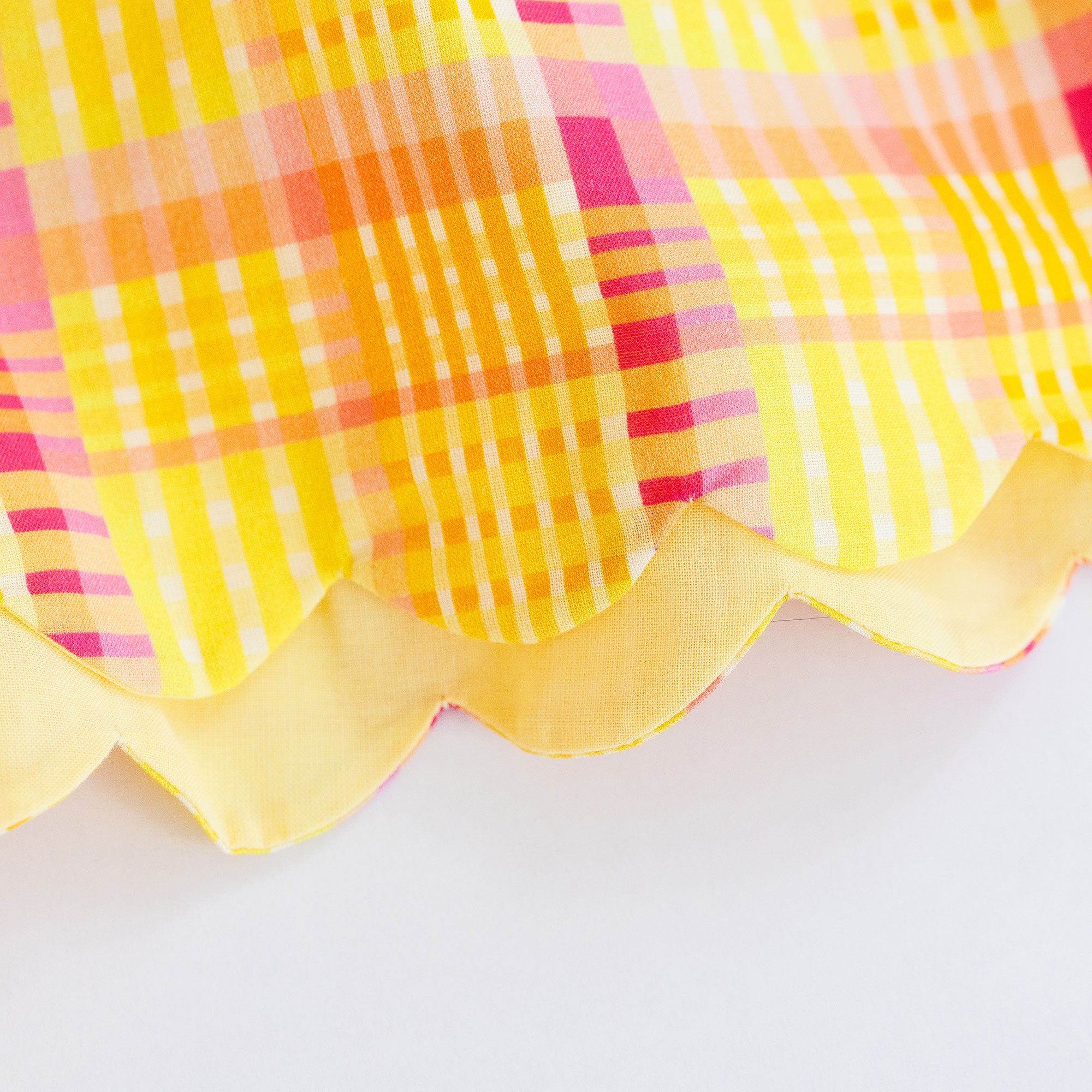 Close-up of a colorful plaid fabric with a scalloped edge on a white background
