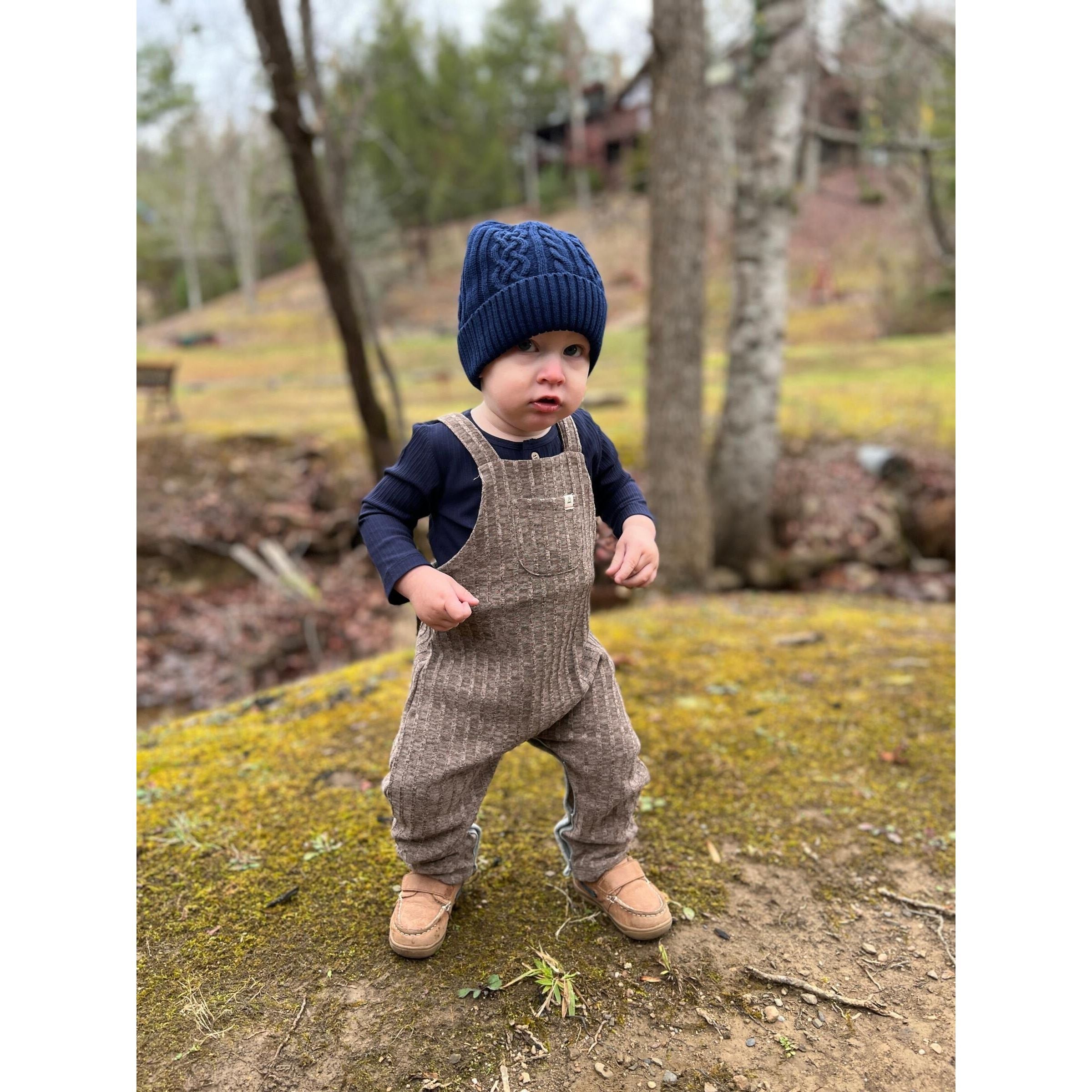 toddler boy wearing navy ribbed longsleeve henley onesie with brown knit overalls