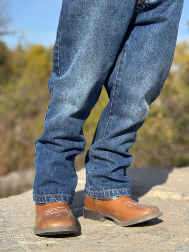 Blue jeans and brown boots on a blurred natural background