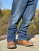 Blue jeans and brown boots on a blurred natural background