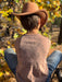 Person wearing a cowboy hat and long sleeve shirt with text sitting in a natural setting.