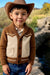 A young boy wearing a brown and cream knit cardigan sweater with a cowboy hat, standing outdoors in front of a blurred natural background.