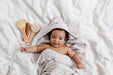 Baby wrapped in a towel with bath brushes on a white background