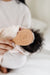 Person holding a wooden baby brush with 'LOU' branding, featuring a baby's hair.