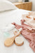 Wooden hairbrushes on a bed with pink clothing and a white pillow.