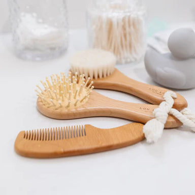 Wooden hairbrush and comb set on a white surface with blurred background