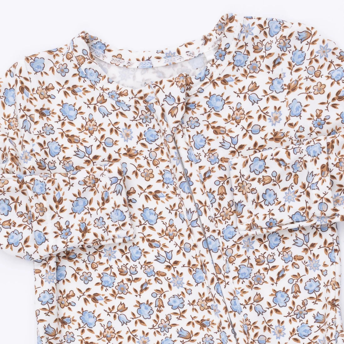 A close-up of a short-sleeve top with a dense floral print featuring light blue flowers and brown leaves on a white background.