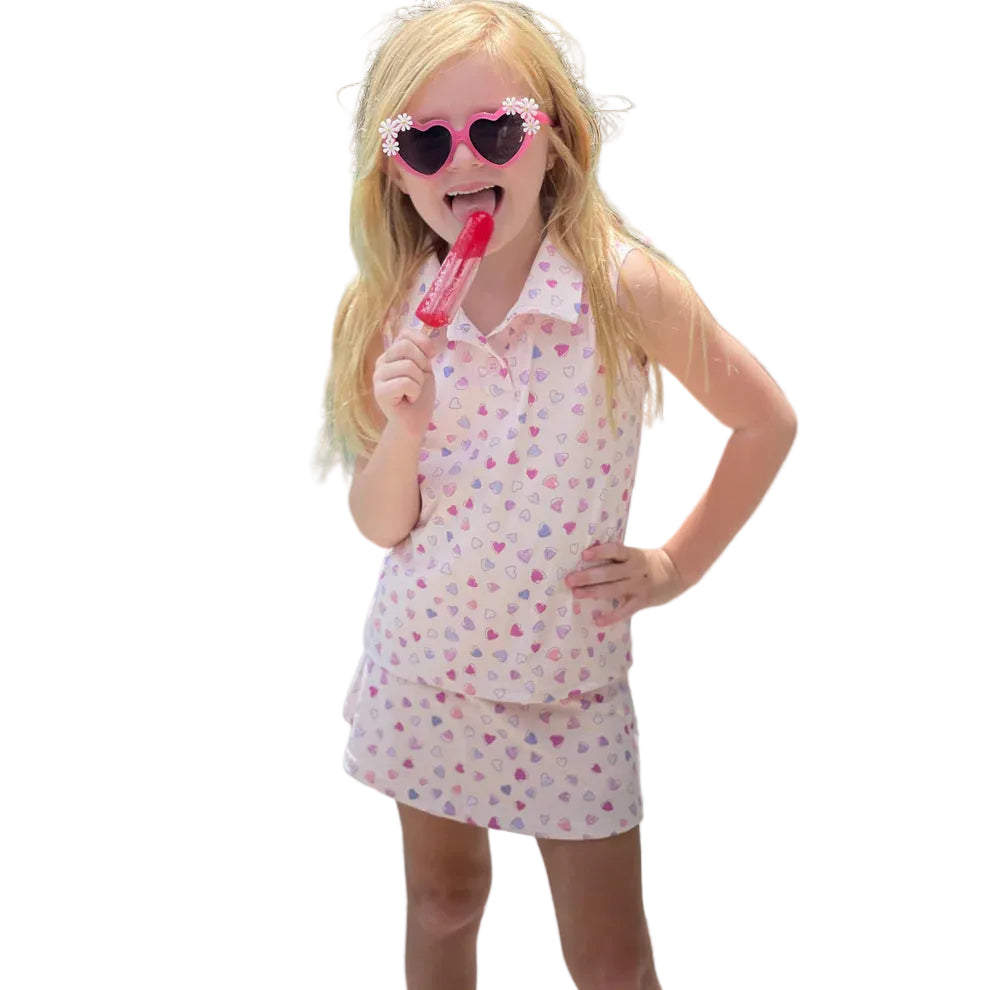 Young girl in a heart patterned polo top and skort.
