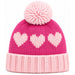 A pink knit beanie hat with a large fluffy pom-pom on top, three light pink hearts knitted across the front, and a ribbed light pink cuff, shown on a plain white background.