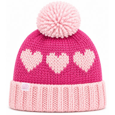 A pink knit beanie hat with a large matching pom-pom on top, featuring three light pink hearts knitted across the upper section and a ribbed light pink cuff. A small embroidered logo patch is visible on the cuff.