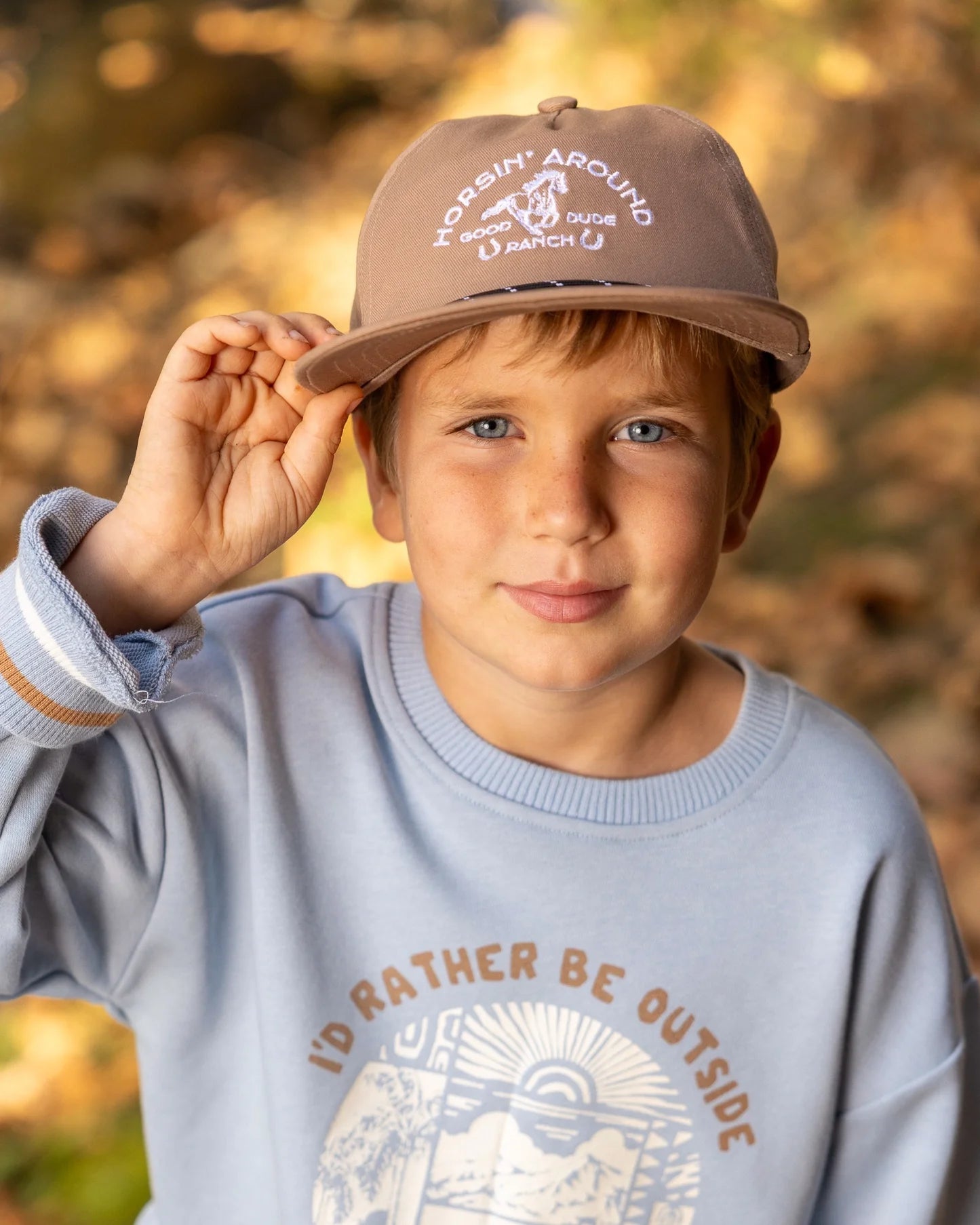 A boy wearing a snapback hat featuring brim rope and embroidered fish patch on the front panel.