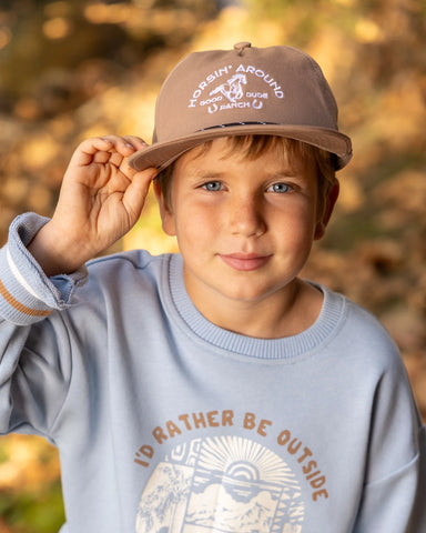 A boy wearing a snapback hat featuring brim rope and embroidered fish patch on the front panel.