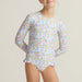 Child wearing a floral long-sleeve swimsuit against a neutral background