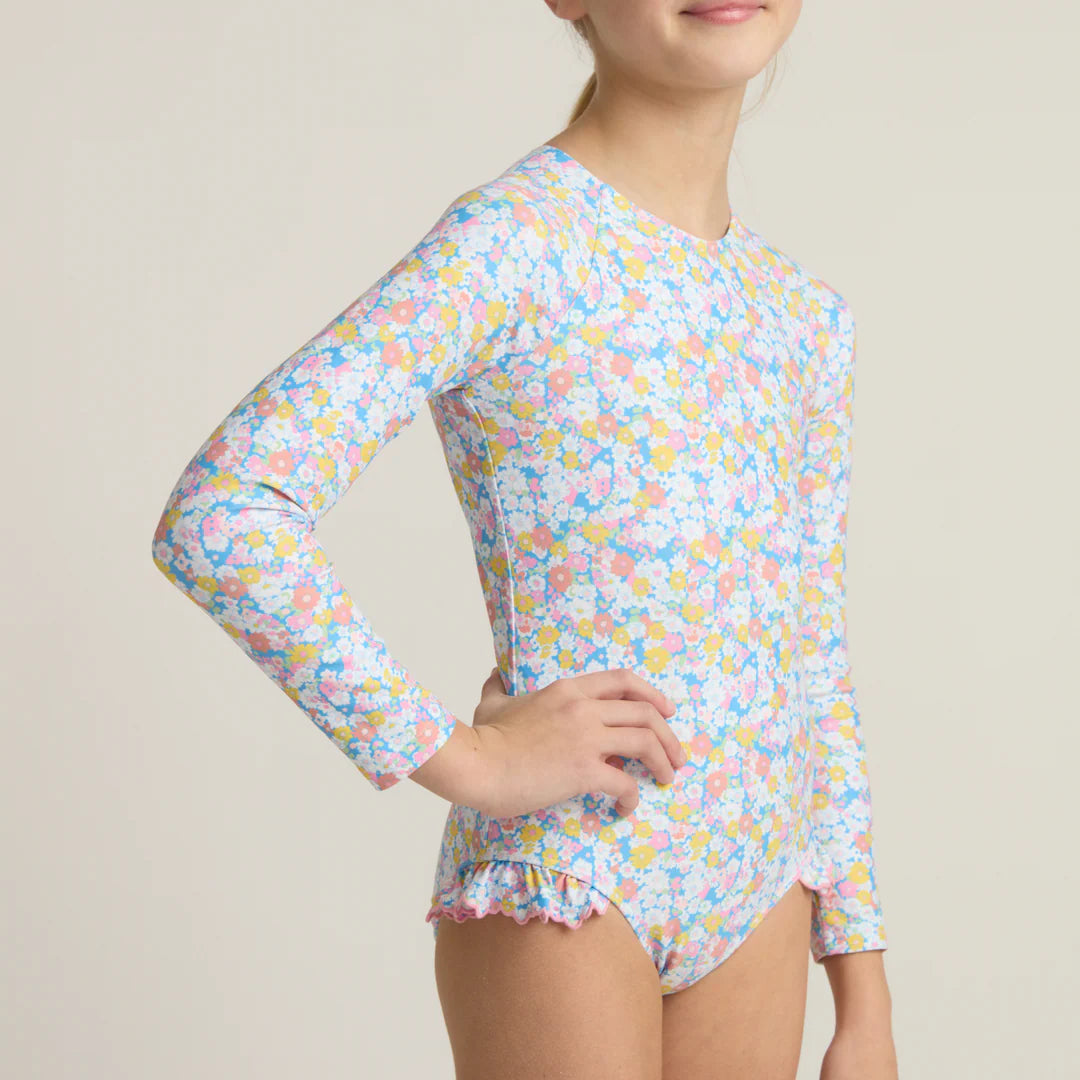 Child wearing a floral long-sleeve swimsuit on a beige background