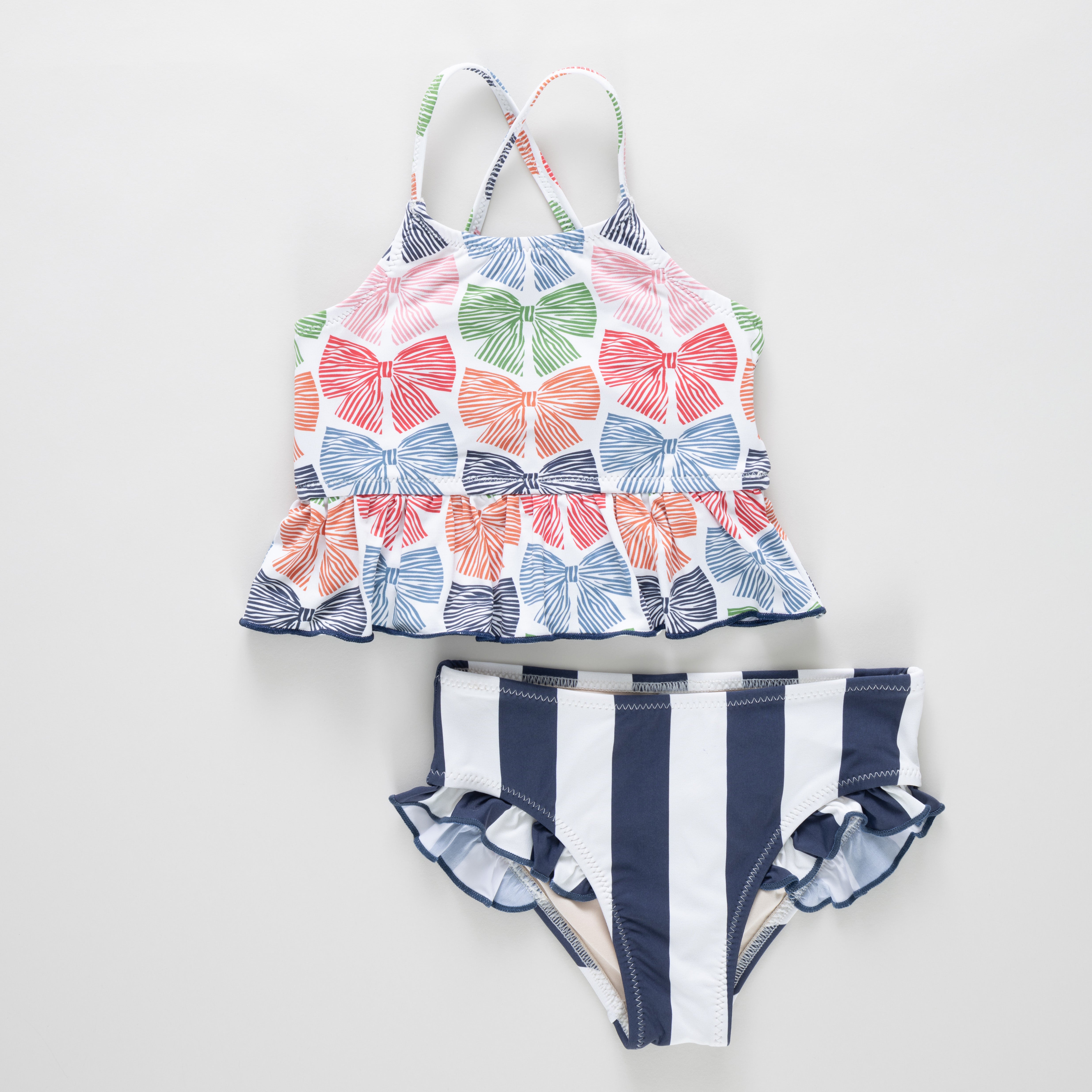Two-piece swimsuit with bow pattern top and striped bottom on a white background