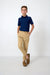 A young boy modeling a navy blue short-sleeve polo shirt and khaki joggers with brown loafers, standing against a clean white studio background.