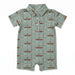 A baby short-sleeve polo romper in sage green with an all-over print of brown logs, pine trees, and figures in canoes, featuring a three-button collar.