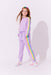 Young girl wearing a lavender tracksuit with rainbow stripes on a white background