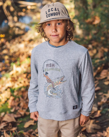A young boy wearing a khaki colored snapback hat featuring brim rope and embroidered "Local Cowboy" graphic on the front panel.