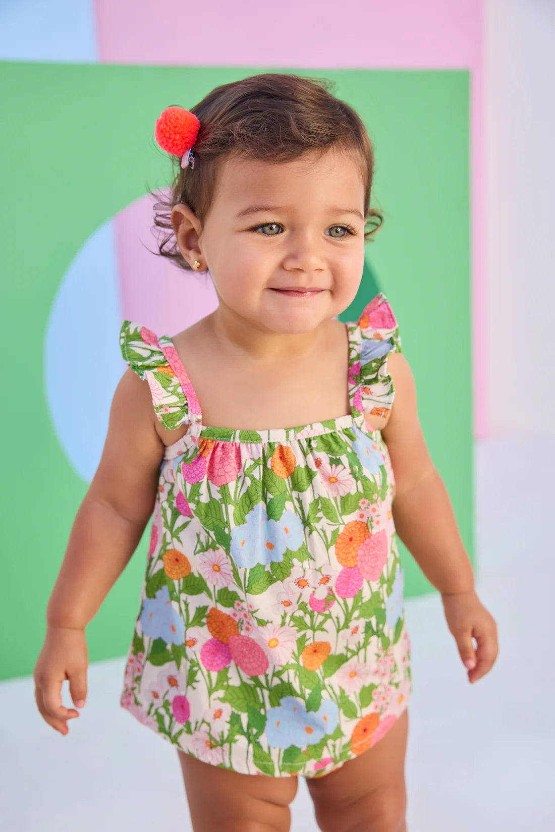 Child wearing a colorful floral bloomer set against a multicolored background