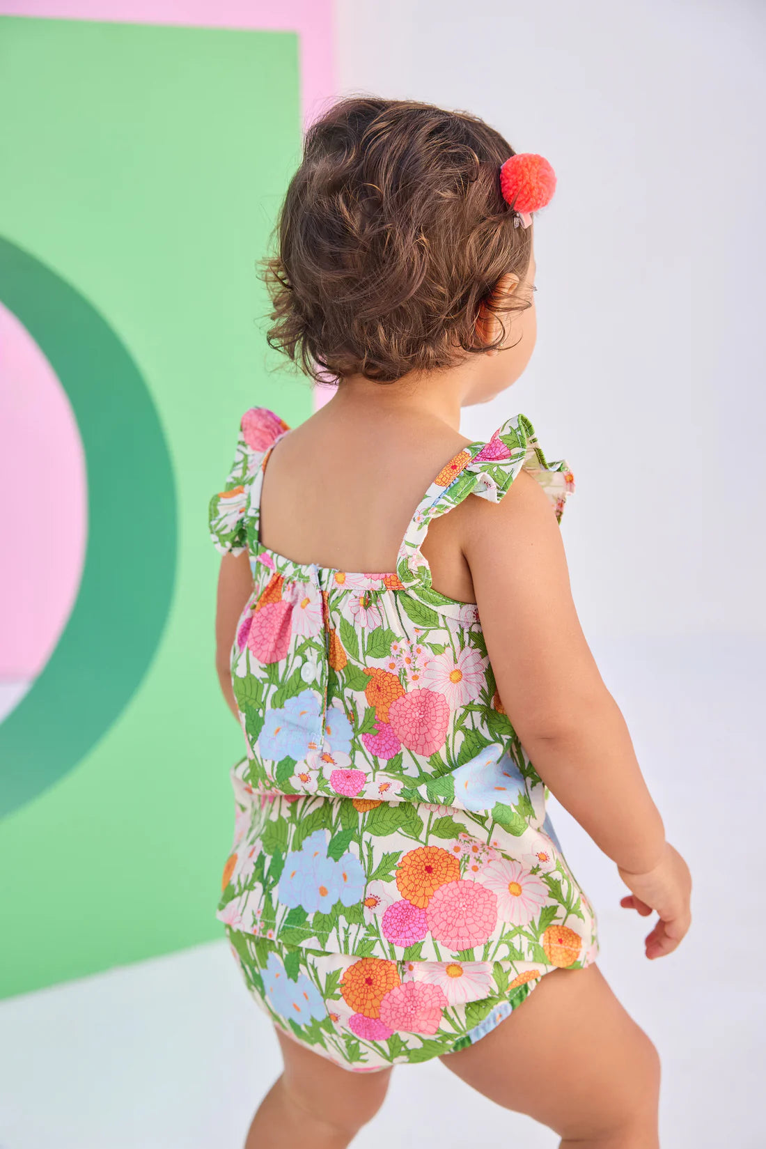 Child wearing a colorful floral bloomer set against a multicolored background