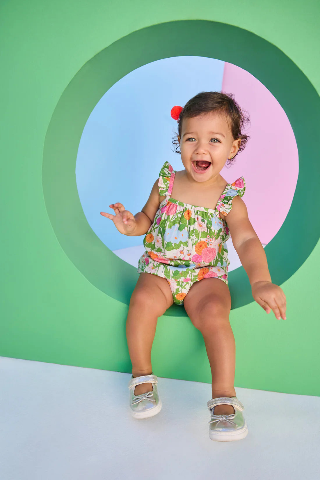 Child wearing a floral bloomer set against a colorful geometric background