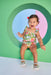Child wearing a floral bloomer set against a colorful geometric background