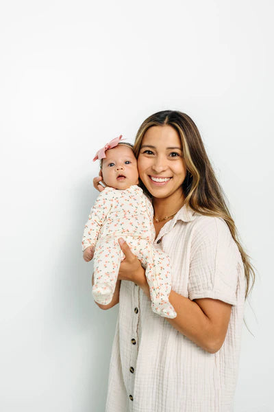 Woman holding a baby against a light background