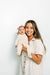 Woman holding a baby against a light background