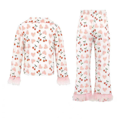A two-piece girls' pajama set featuring a long-sleeve top and matching pants. The set has an all-over cherry print on a white background, with light pink heart patterns and pink ruffled trim on the cuffs and hems.