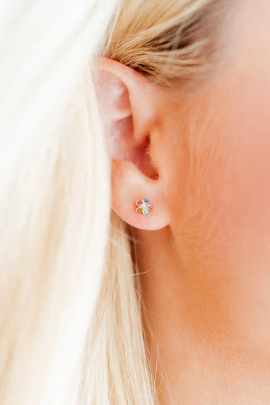 Close-up of an ear wearing a colorful earring with blonde hair.