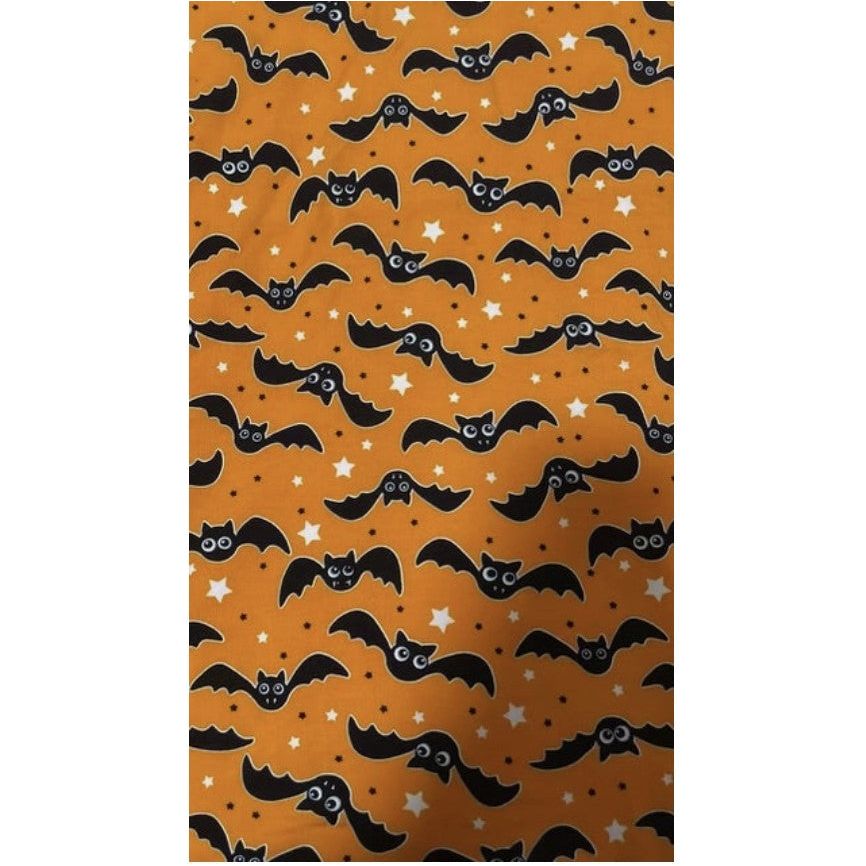 up close of orange with black glow in the dark bats print fabric